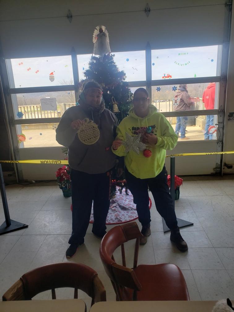 Stephanie Campbell and Stacey Evernote with ornaments in front of Christmas tree